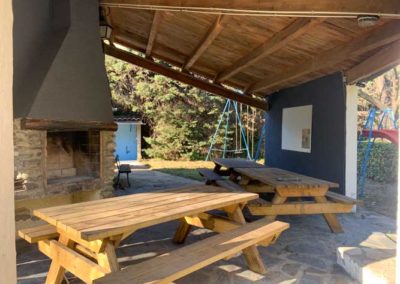 Hall gris avec tables de picnic et barbecue au camping le petit baigneur